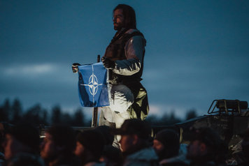 Soldier holding the NATO flag.