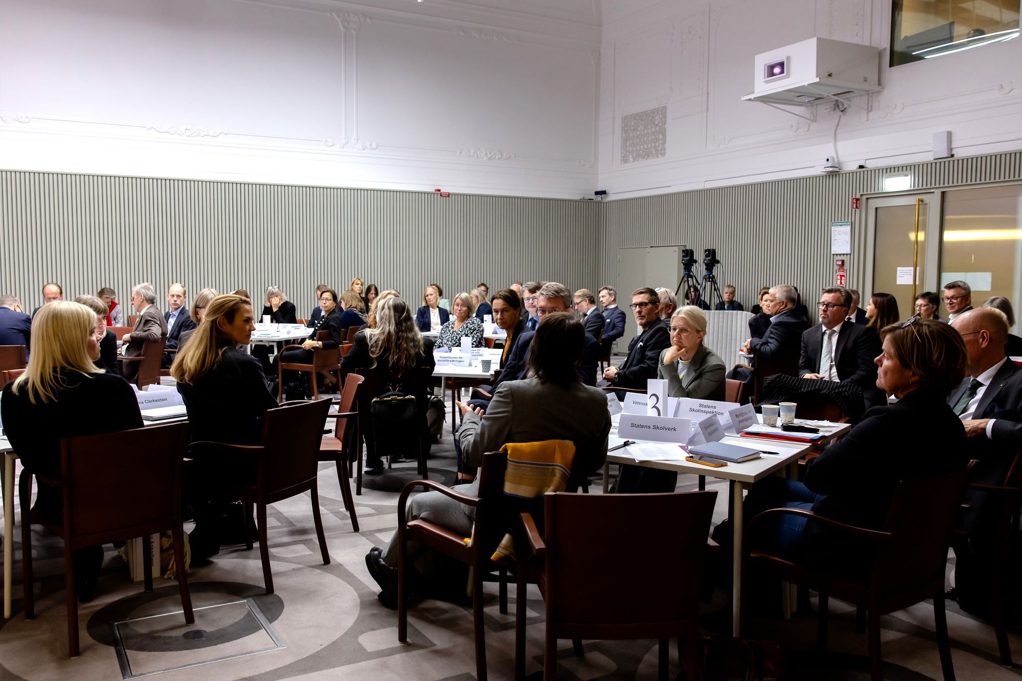 A number of persons sitting in a room.