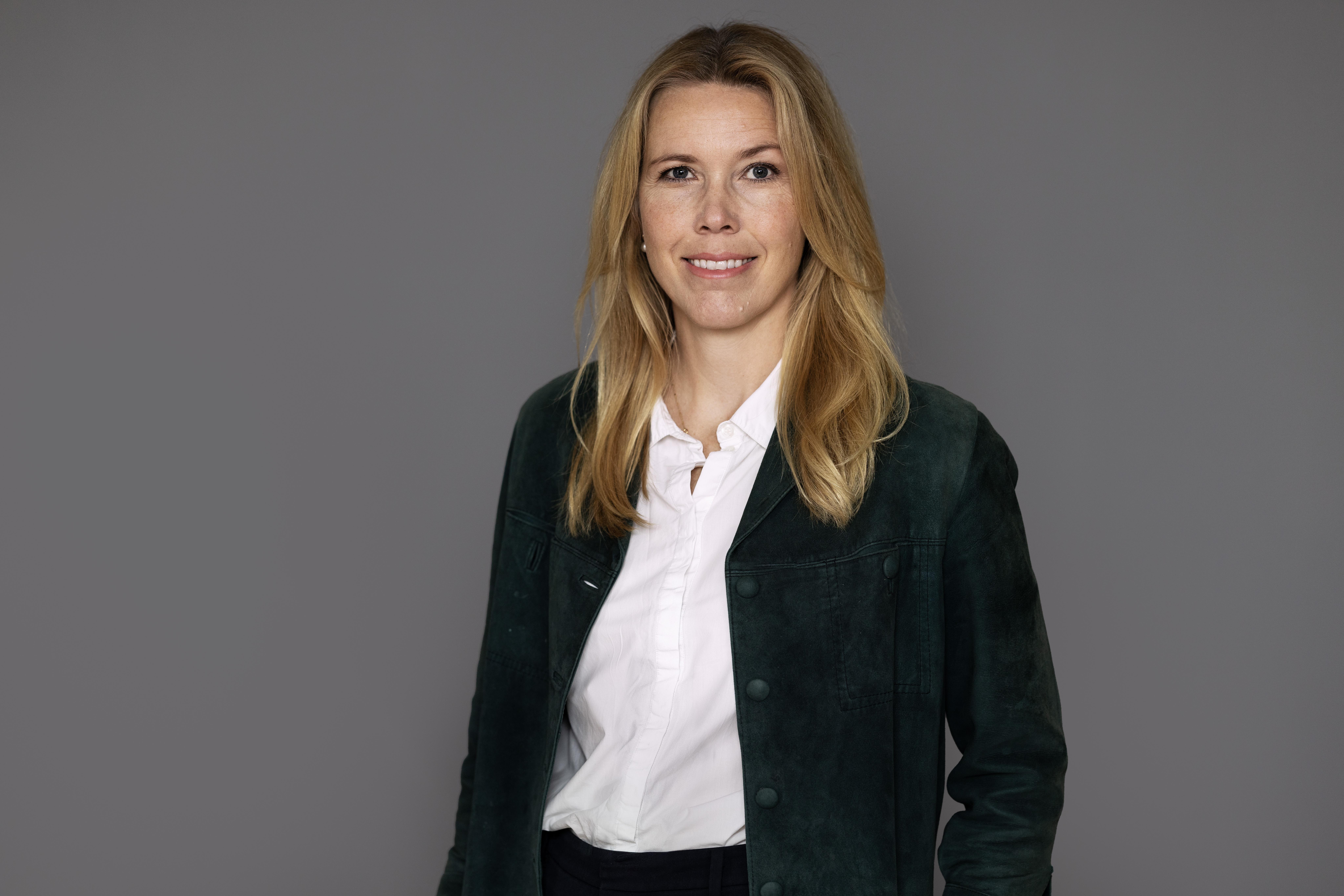 Blond kvinna mot grå vägg