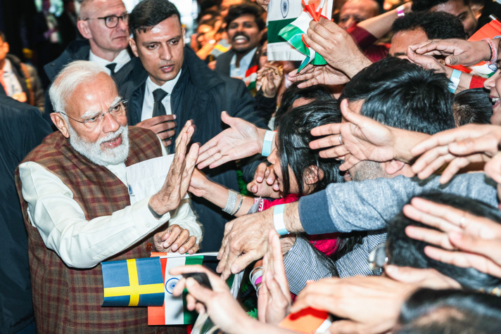 India’s Prime Minister Modi meets a large group of people holding Swedish and Indian flags.