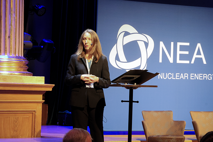 A woman holding a speech standing on a stage.