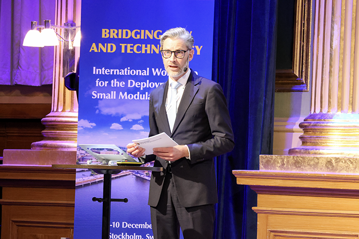 A man holding a speech standing on a stage.