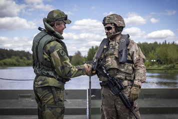 A Swedish and an American soldier shaking hands.