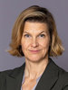 Minister for Gender Equality Nina Larsson stands in front of a gray wall and looks into the camera.