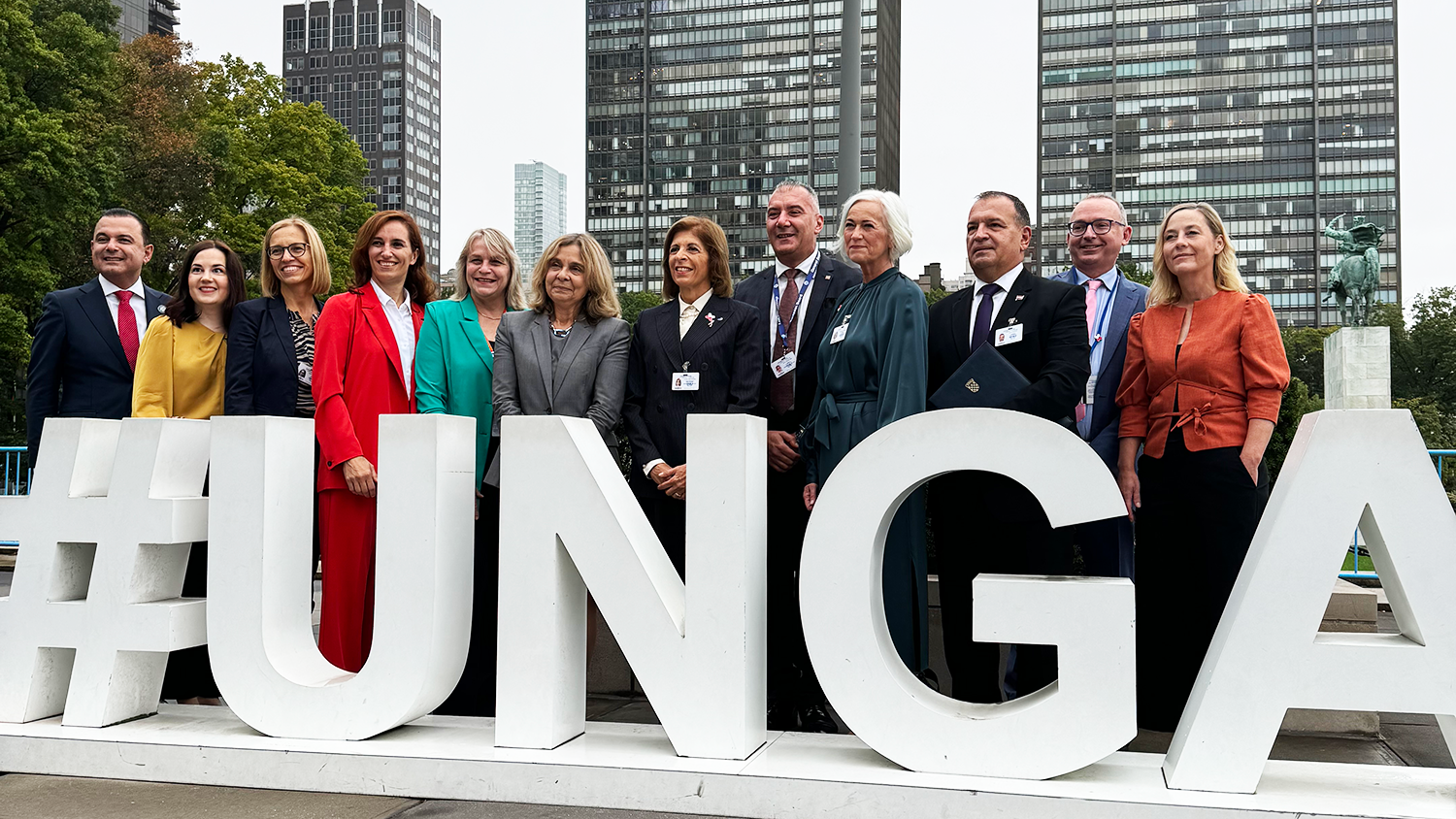 A group of people standing behind a big sign with the text "UNGA" on it.